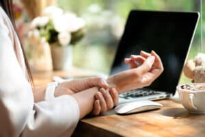 Closeup,Woman,Holding,Her,Wrist,Pain,From,Using,Computer.,Office