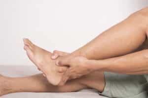 A close-up shot of a man with ankle arthritis holding his ankle